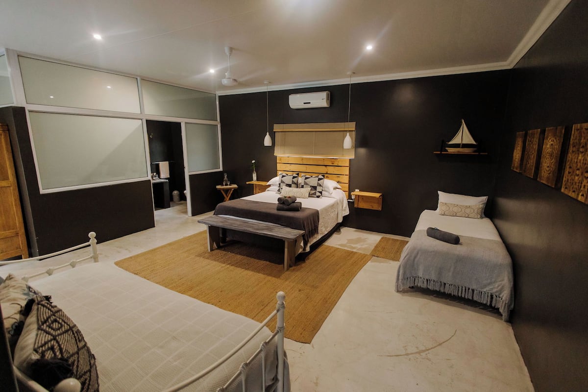 A modern bedroom with a large bed, bedside tables, a bench, and a smaller bed.