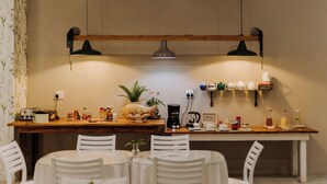 A cozy dining area with a wooden table, white chairs, and a hanging light fixture. - iGwalagwala Guest House (St. Lucia)