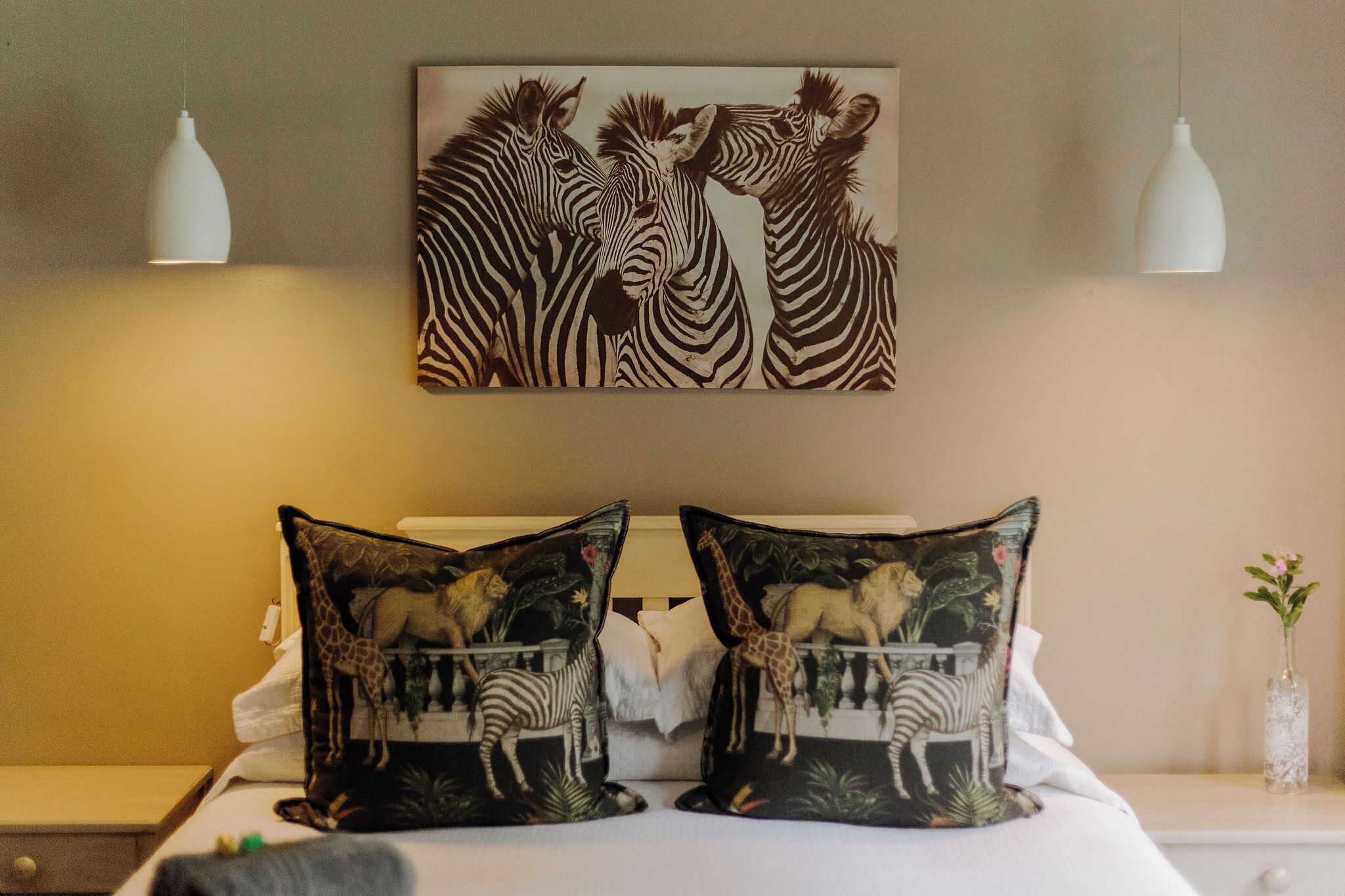 A bedroom with a zebra-themed bedspread, matching pillows, and a zebra painting on the wall.