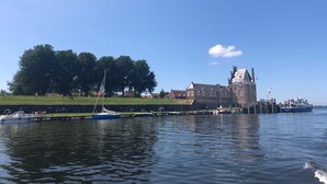 A waterfront view with a historic building, boats, and a grassy area. - Hoevehotel Hof Christina (Vrouwenpolder)