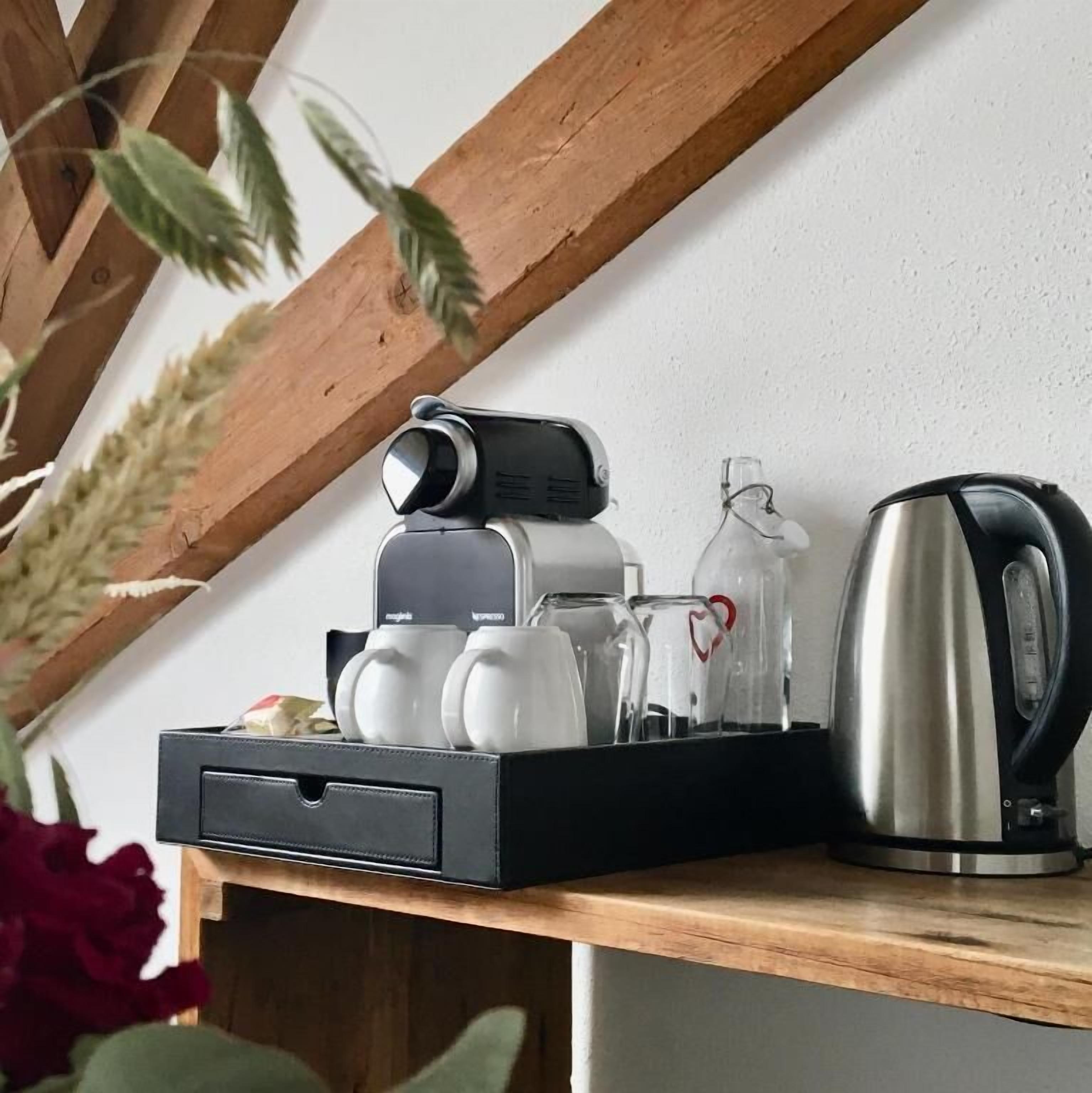 A coffee machine with two cups, a glass carafe, and a kettle on a wooden counter.