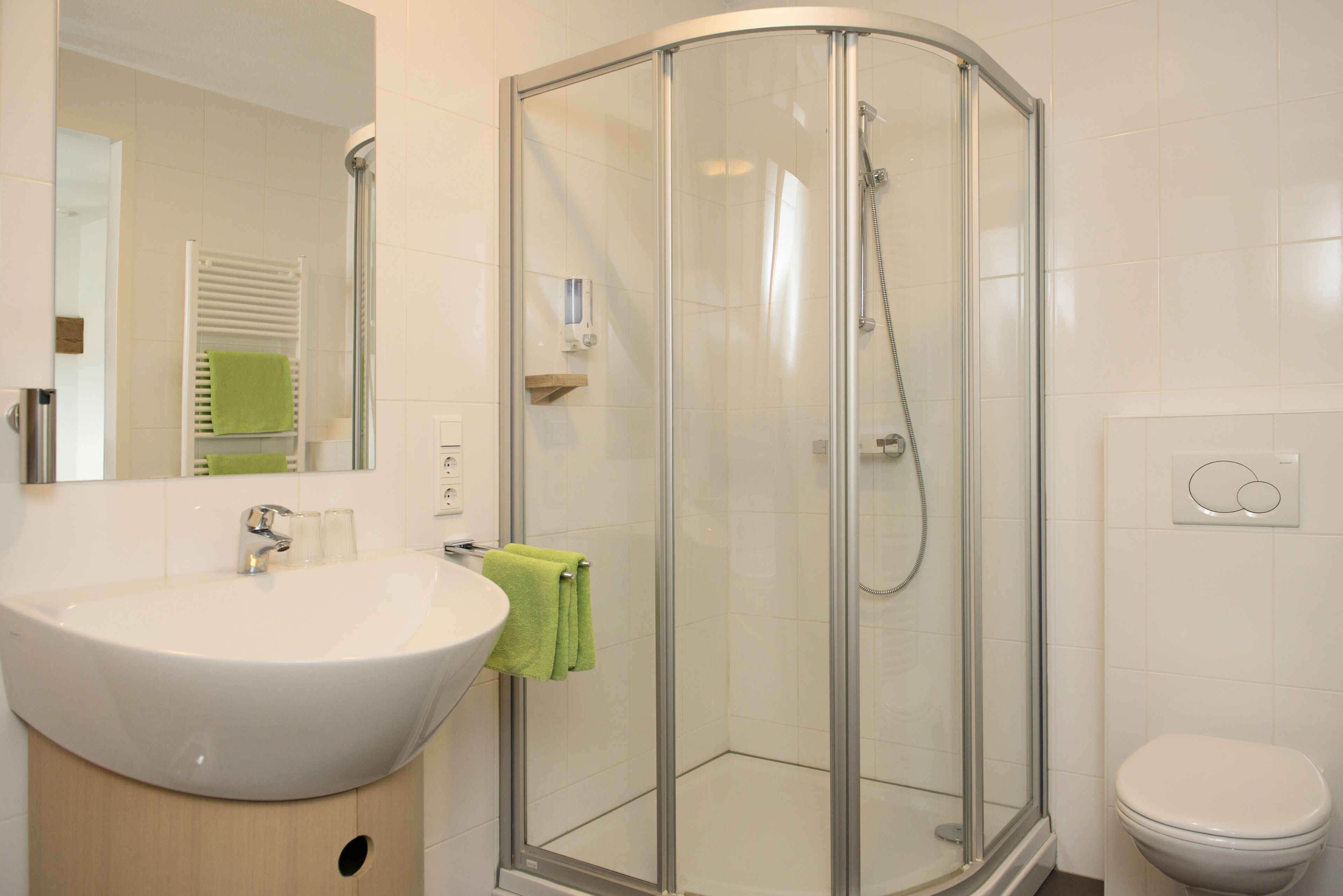 Een moderne badkamer met een douchecabine van glas, een witte wastafel en een toilet.