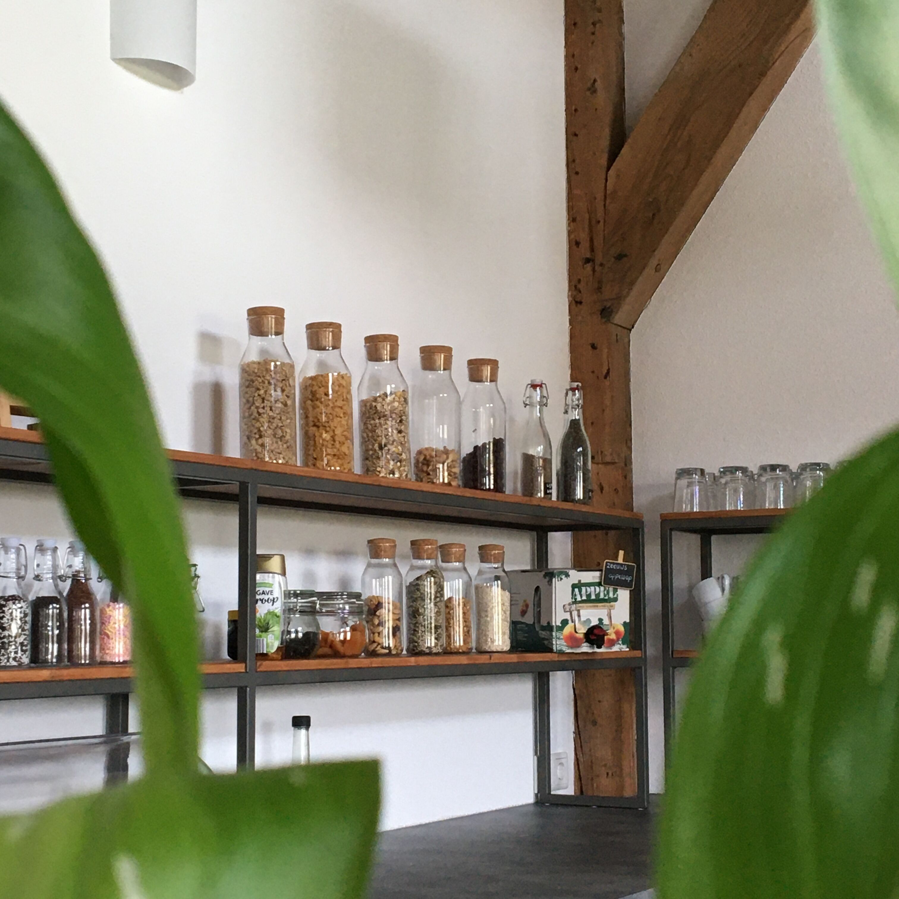 A kitchen shelf with various glass jars containing different food items.