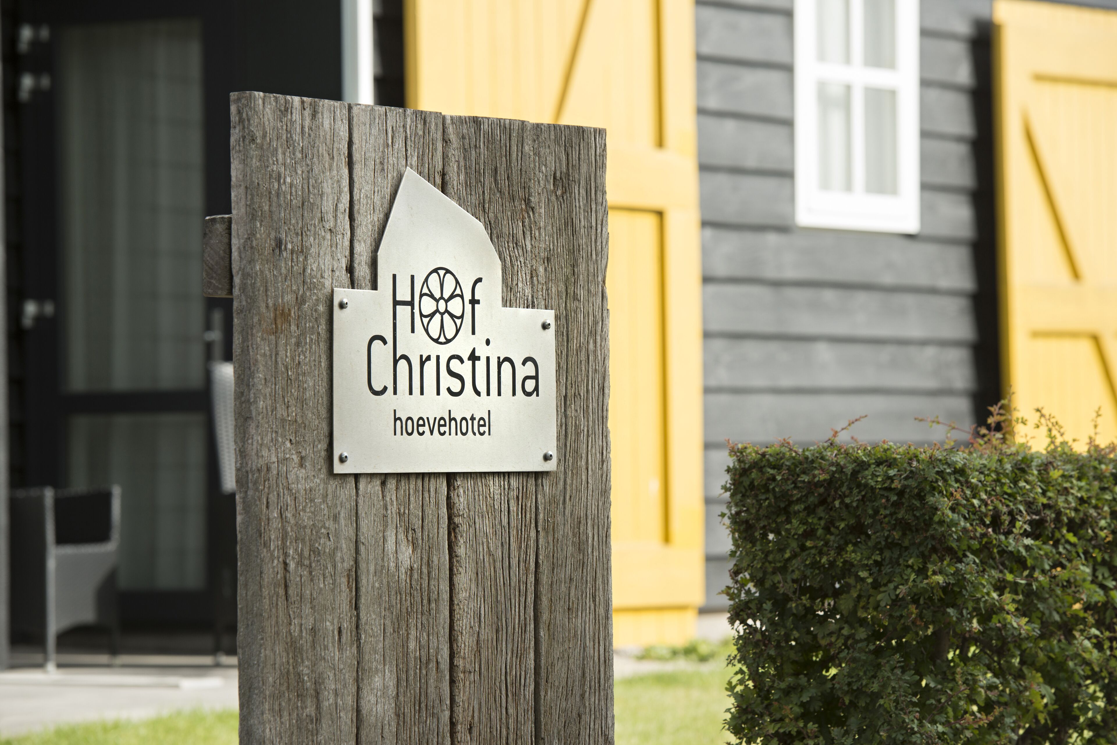 Une enseigne en bois portant l’inscription « Hoof Christina hoevehotel », qui indique le nom de l’établissement.