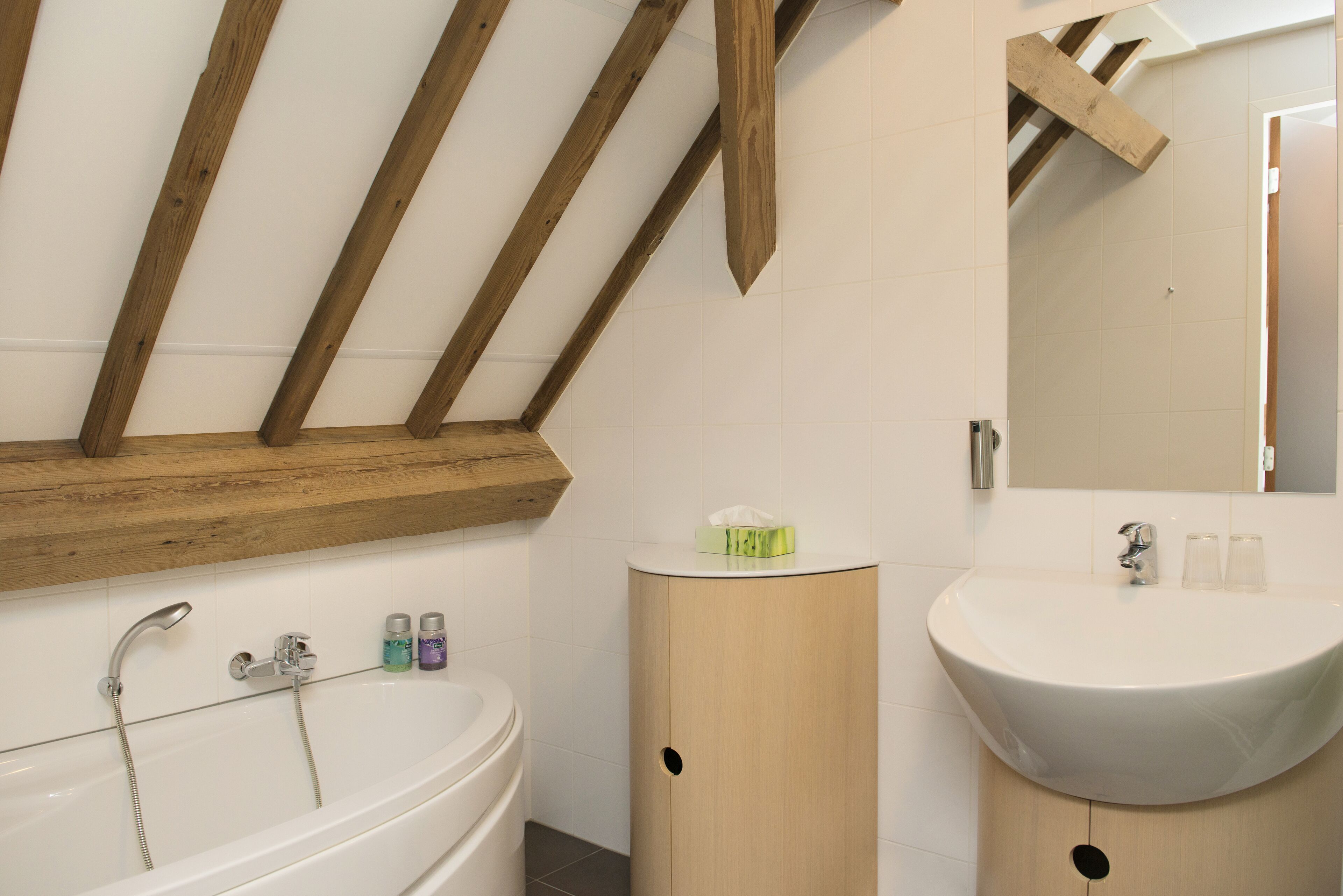 Une salle de bain moderne avec une baignoire sur pieds, un meuble-lavabo en bois et un miroir au-dessus du lavabo.
