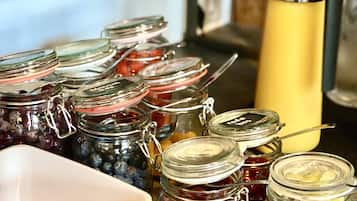 Diversos alimentos, incluyendo frascos de mermelada de frutas, un bol de crema de chocolate y un cartel que indica yogur de frutas.