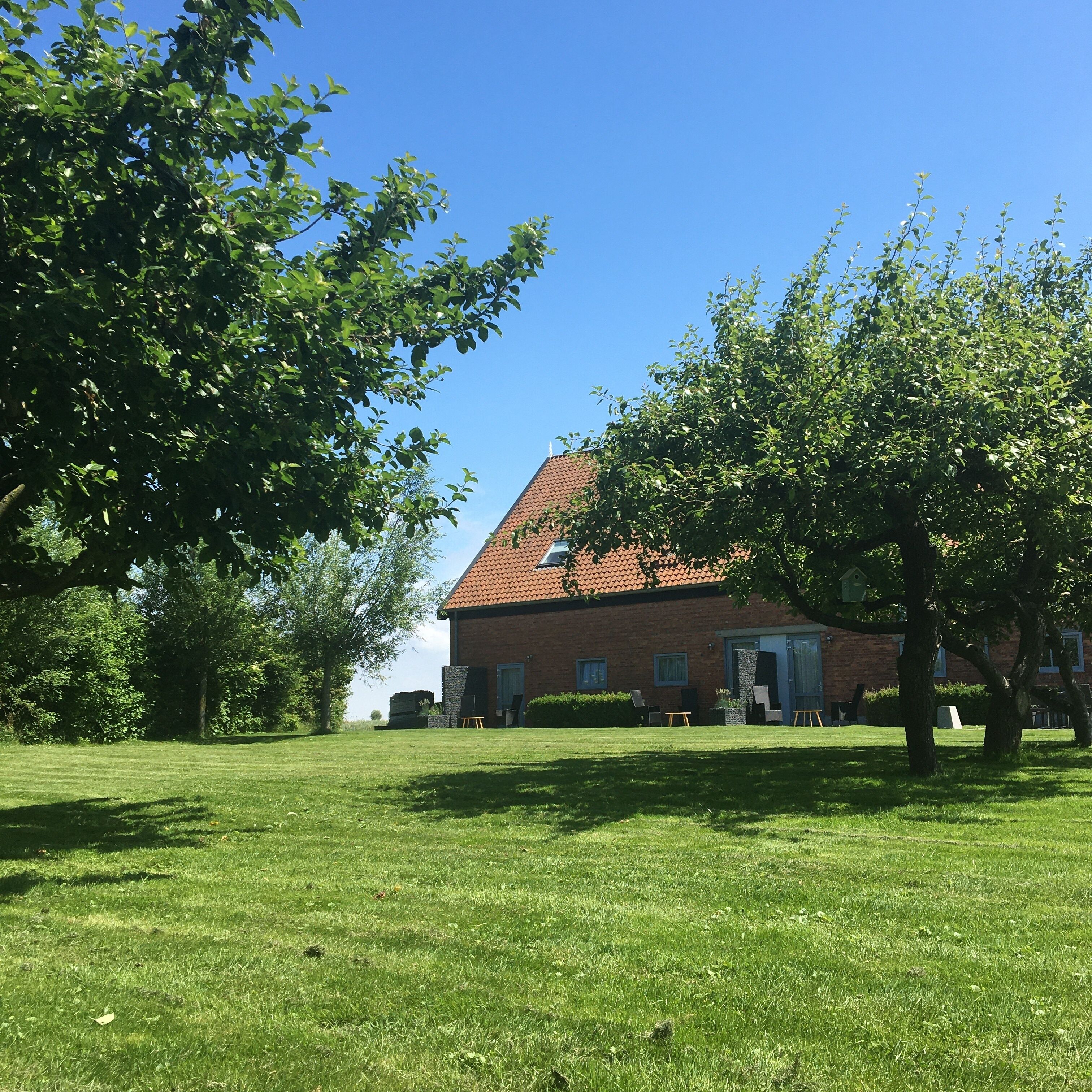 A brick building with a sloped roof, surrounded by a well-maintained lawn and trees.