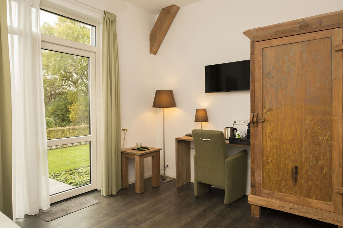 A room with a wooden desk, two lamps, a television, and a cabinet.