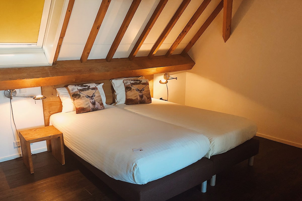 A bedroom with a large bed, wooden headboard, bedside lamps, and a small wooden nightstand.