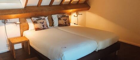 A bedroom with a large bed, wooden headboard, bedside lamps, and a small wooden nightstand.
