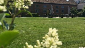 A building with a tiled roof, a grassy lawn, and outdoor seating. - Hoevehotel Hof Christina (Vrouwenpolder)