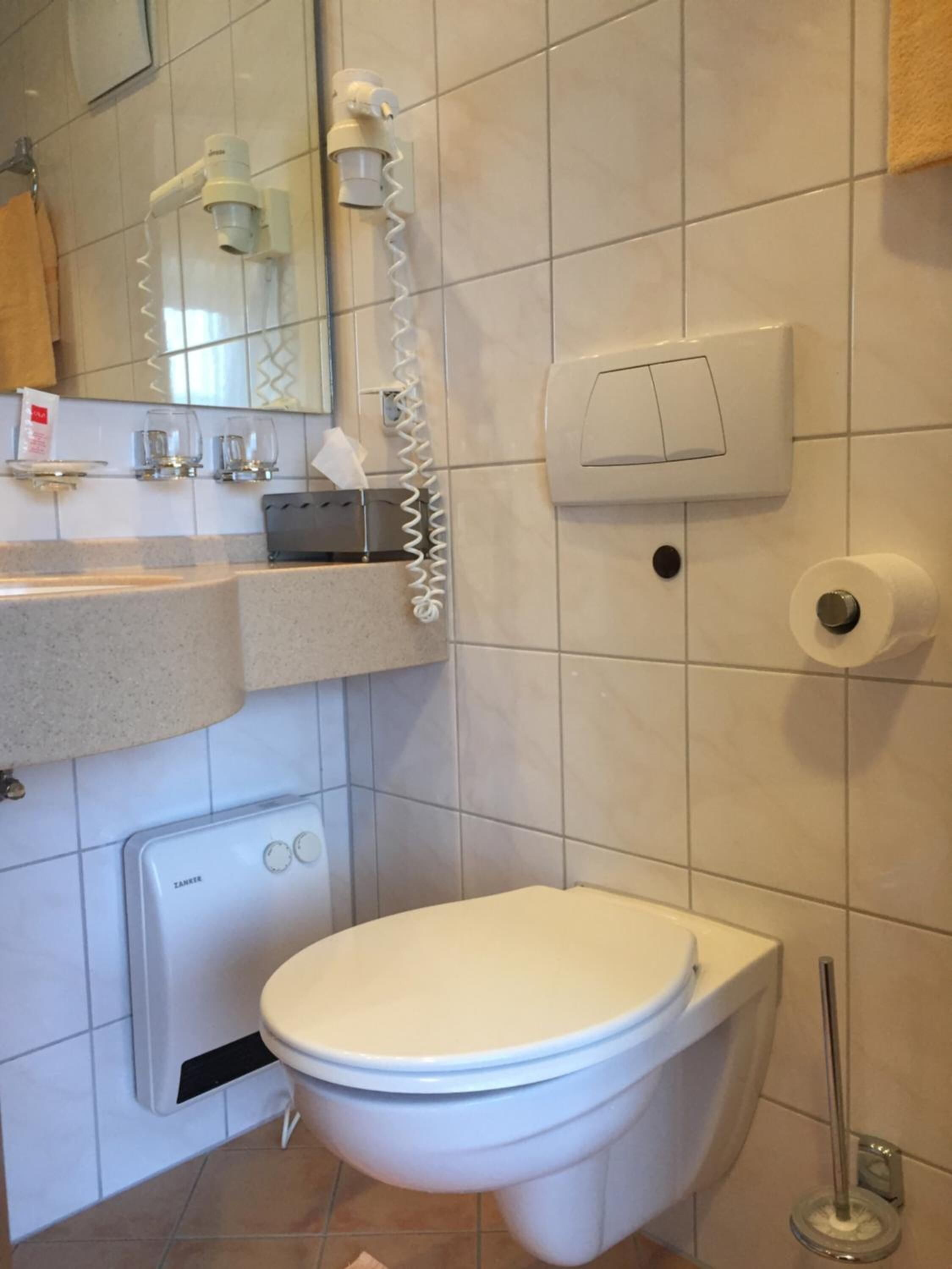 Un bagno moderno con un water, un lavandino, uno specchio e un asciugamani ad aria.