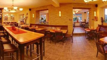 Un ristorante con tavoli e sedie di legno, pareti in pietra e un'illuminazione calda e accogliente.