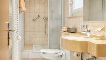 Een moderne badkamer met een douche, toilet en wastafel.