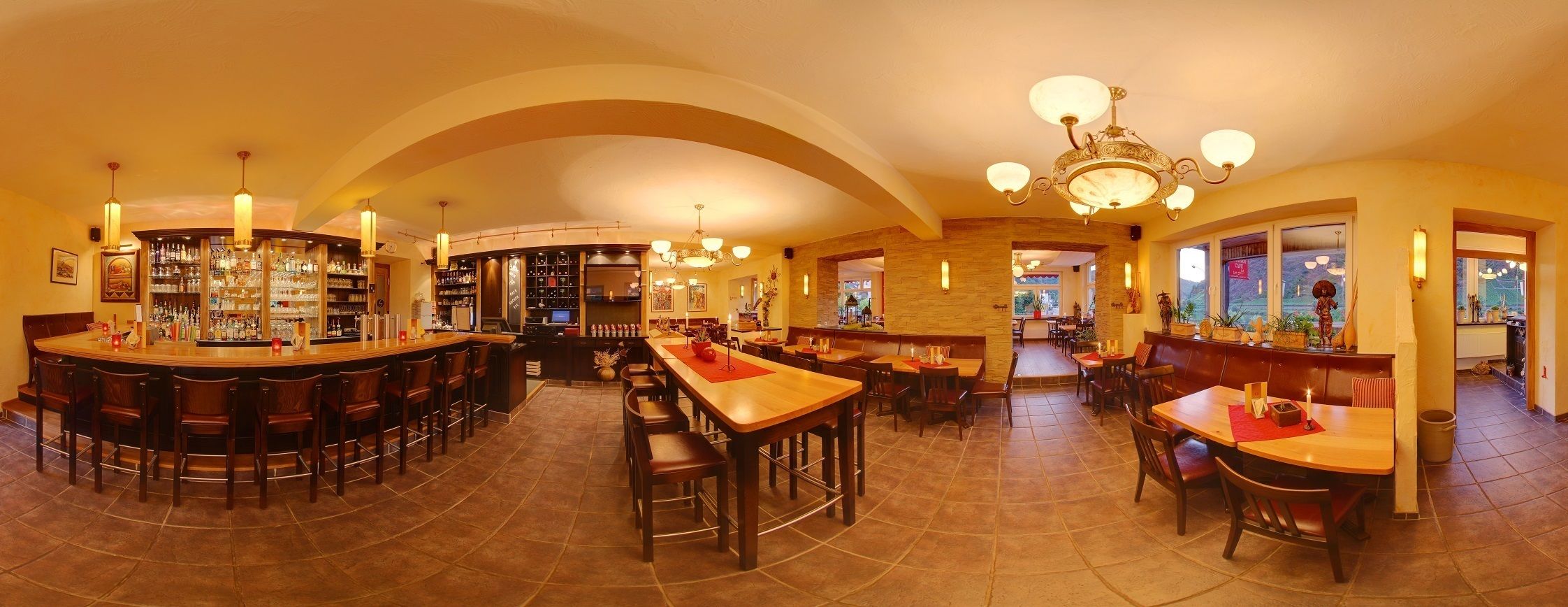 Uma área de bar espaçosa com diversas opções de assento, incluindo banquetas e mesas, e um interior bem iluminado com um lustre.
