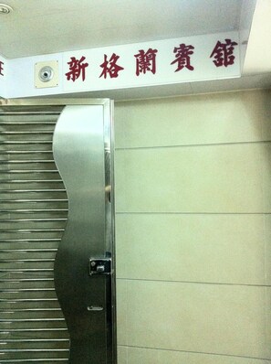 A metal door with a handle and a sign above it. - New Grand Guest House (Kowloon)