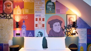 Une chambre d’hôtel avec un grand lit, une carte accrochée au mur, ainsi que divers affiches et œuvres d’art.