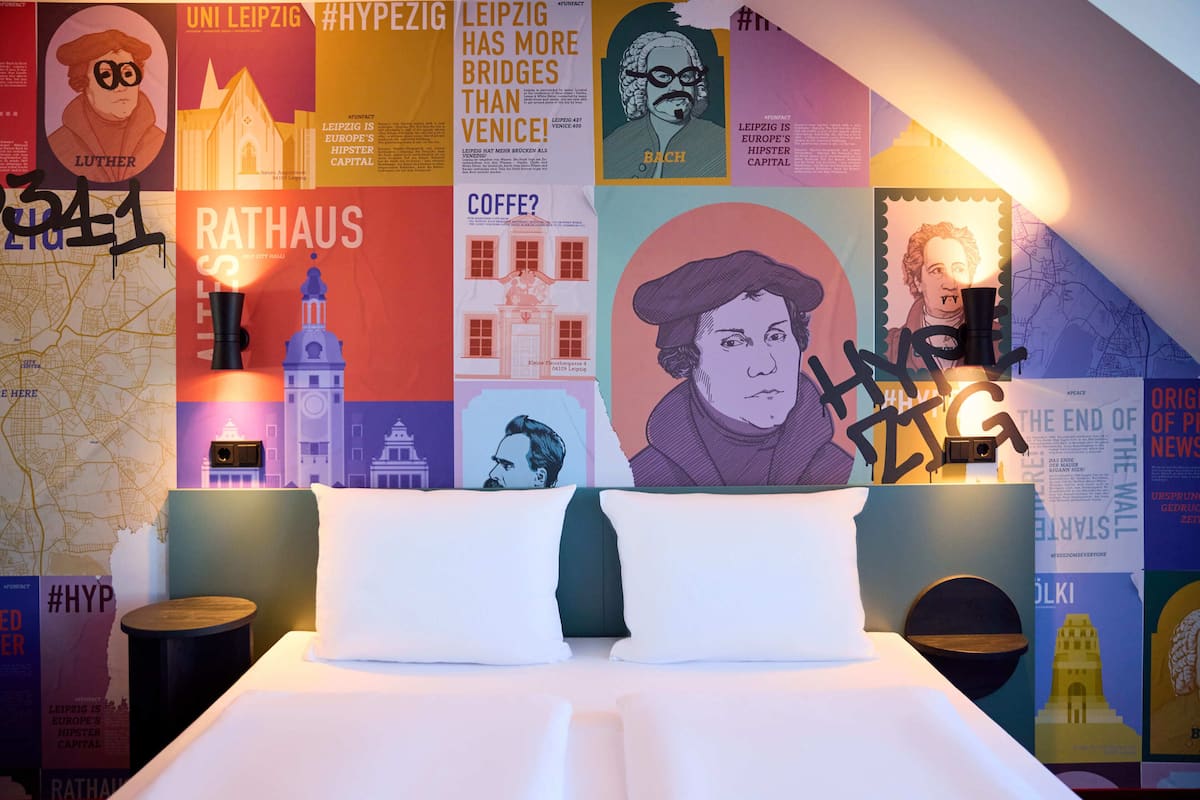Una habitación de hotel con una cama grande, un mapa en la pared y varias ilustraciones y obras de arte.