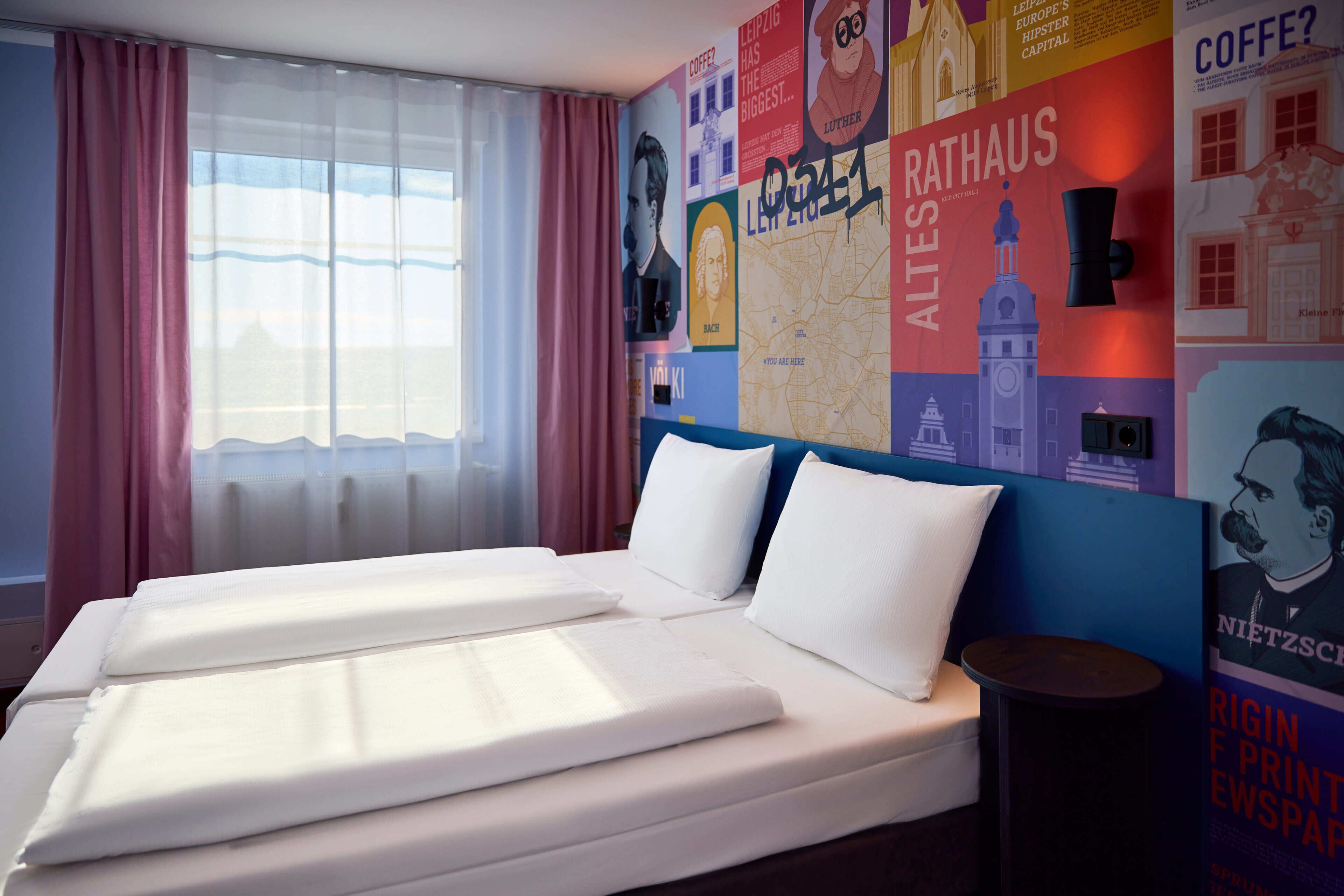 Une chambre d’hôtel avec un grand lit, une petite table et un mur décoré d’affiches.