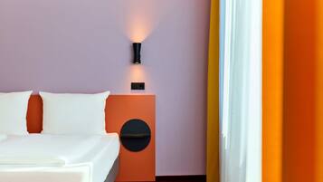 Habitación de hotel con cama, mesita de noche con lámpara y un adorno circular en la pared.