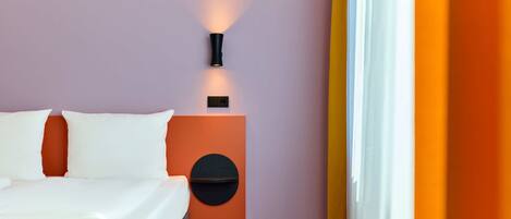 Une chambre d’hôtel avec un lit, une table de chevet avec une lampe et un élément décoratif circulaire fixé au mur.