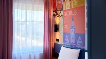 Ein Hotelzimmer mit einem Bett, einer Karte an der Wand und einem Vorhangfenster.