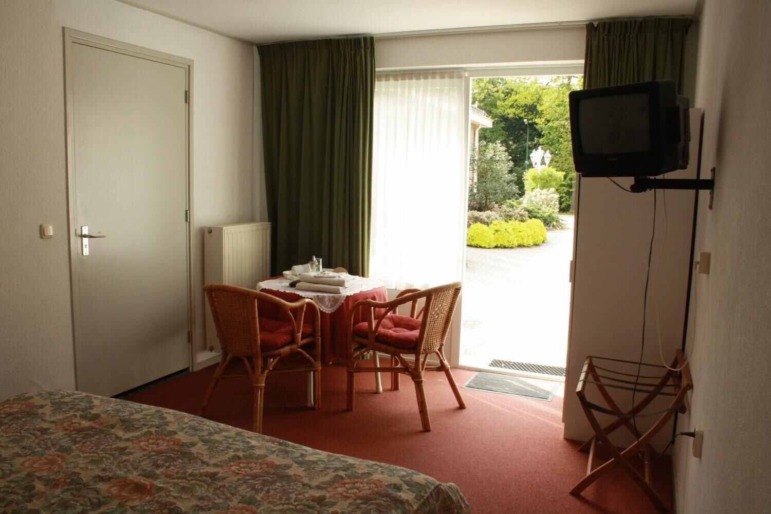 Habitación de hotel con cama, una mesa y sillas, televisión y vistas al exterior.