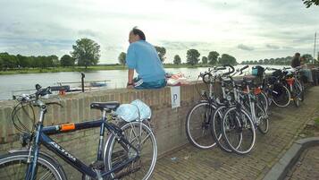 A man sitting on a wall overlooking a river with bicycles parked nearby.