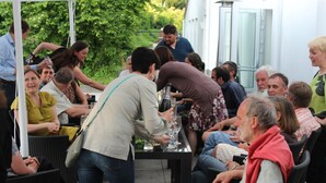 Eine Gruppe von Personen sitzt an einem Tisch im Freien, während ein Kellner sie bedient.