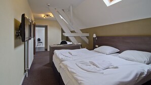 Ein Hotelzimmer mit zwei Betten, einem Schreibtisch, einem Stuhl, einem Fernseher und einem Oberlicht.