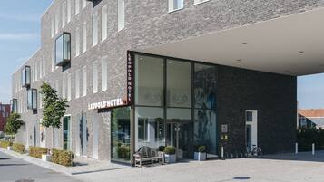 A LEOPOLD HOTEL with a modern facade, large windows, and a covered entrance area.