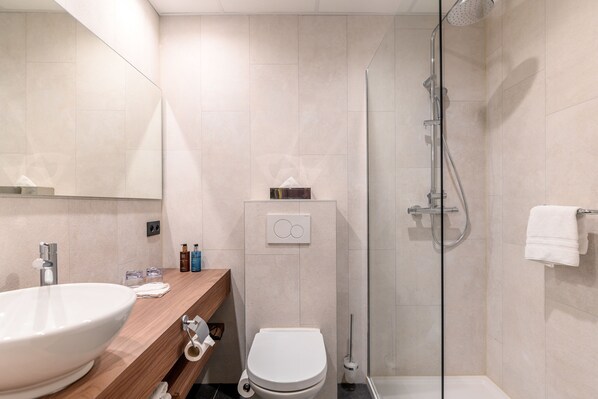 Un baño moderno con un lavamanos grande, inodoro y cabina de ducha de vidrio.