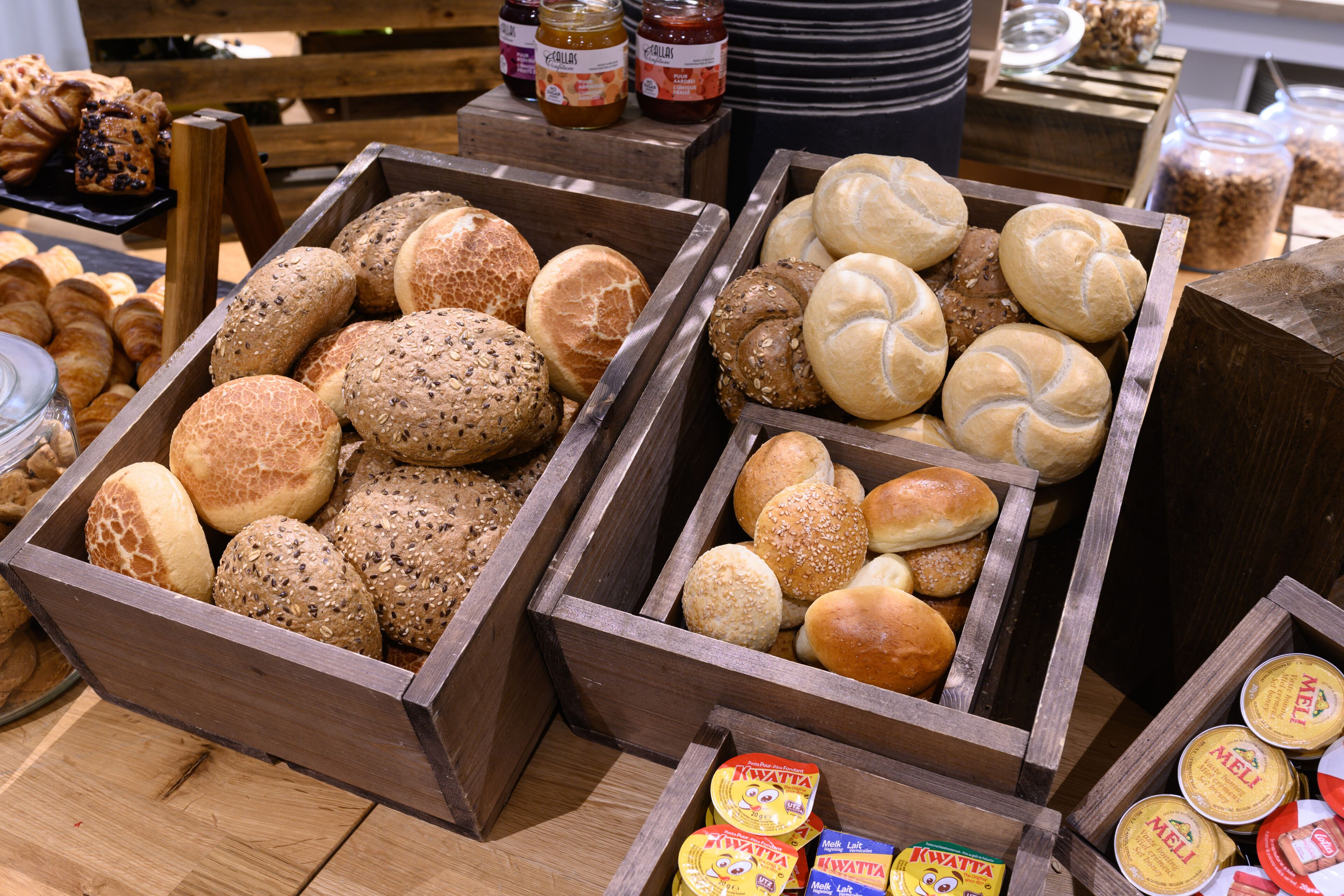 Wooden display cases filled with various types of bread and rolls.