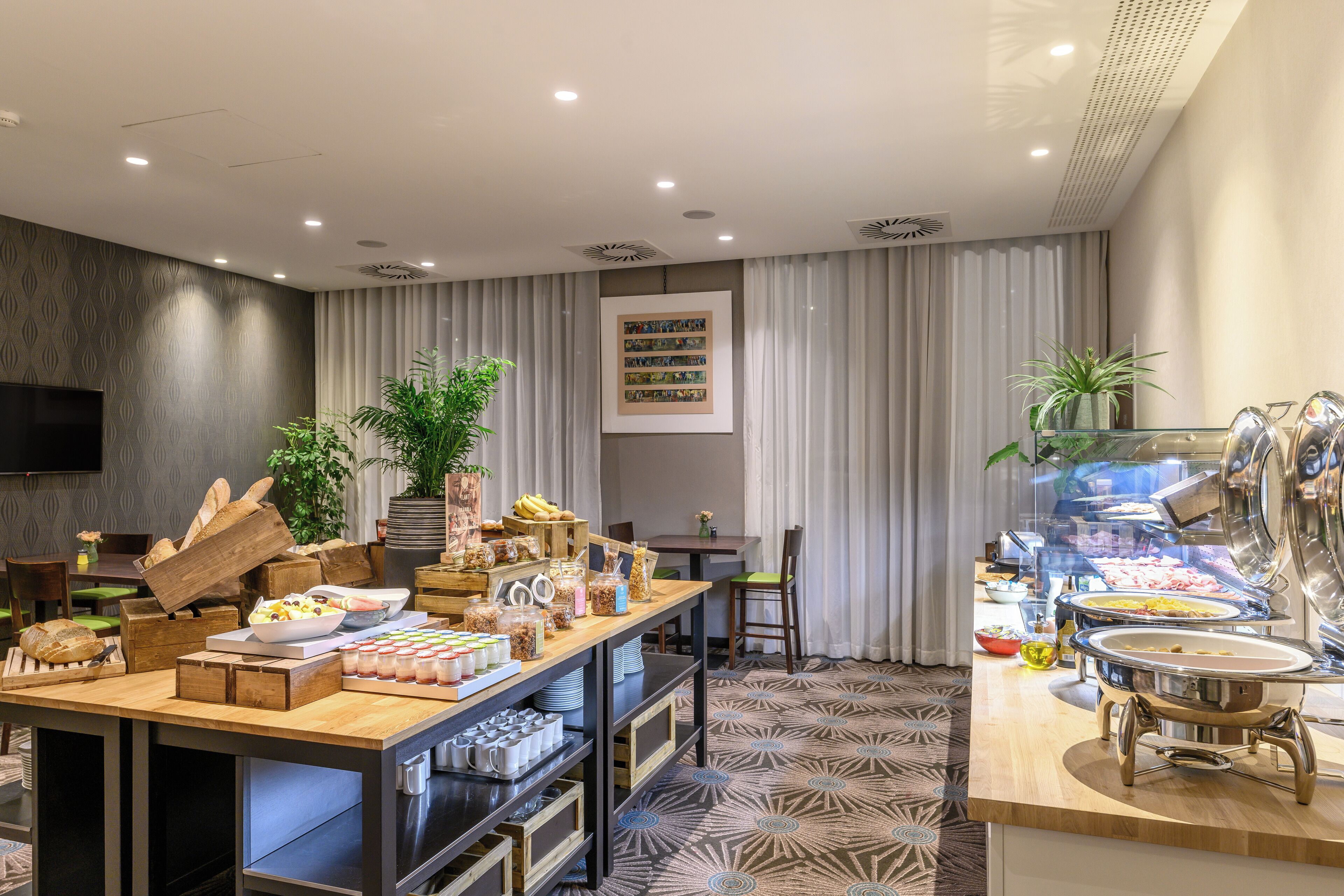 A buffet setup with various food items, a television, and a plant in a hotel room.