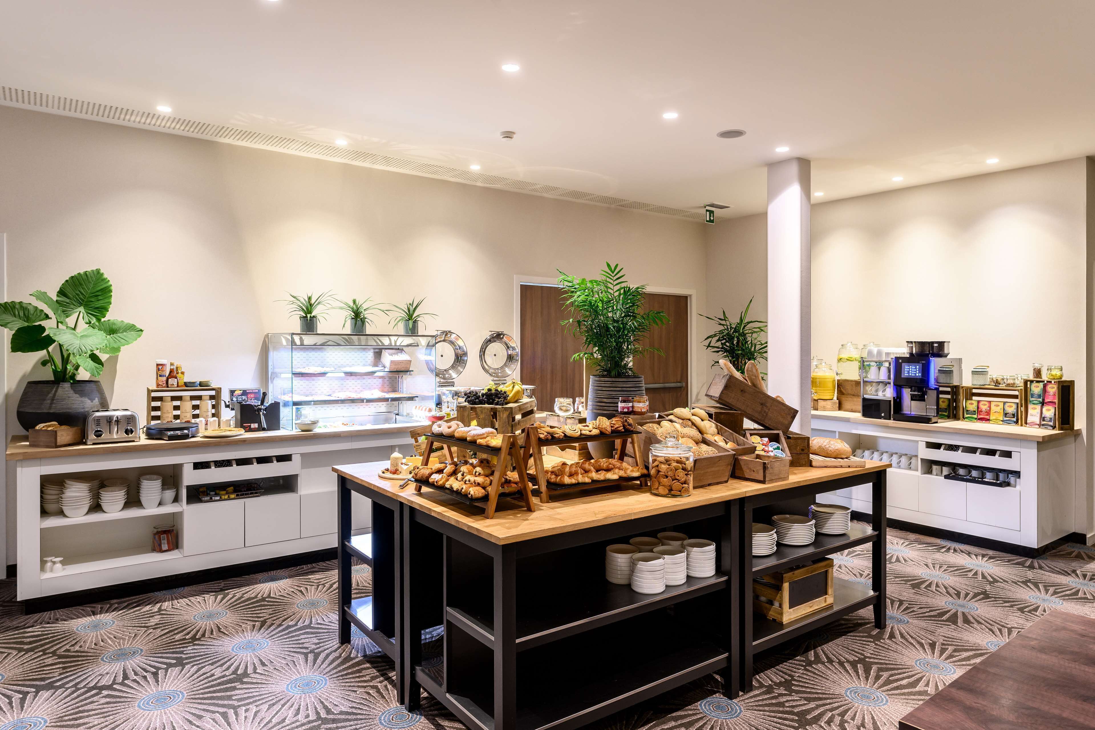 A modern breakfast area with a variety of food items, a coffee station, and a seating area.
