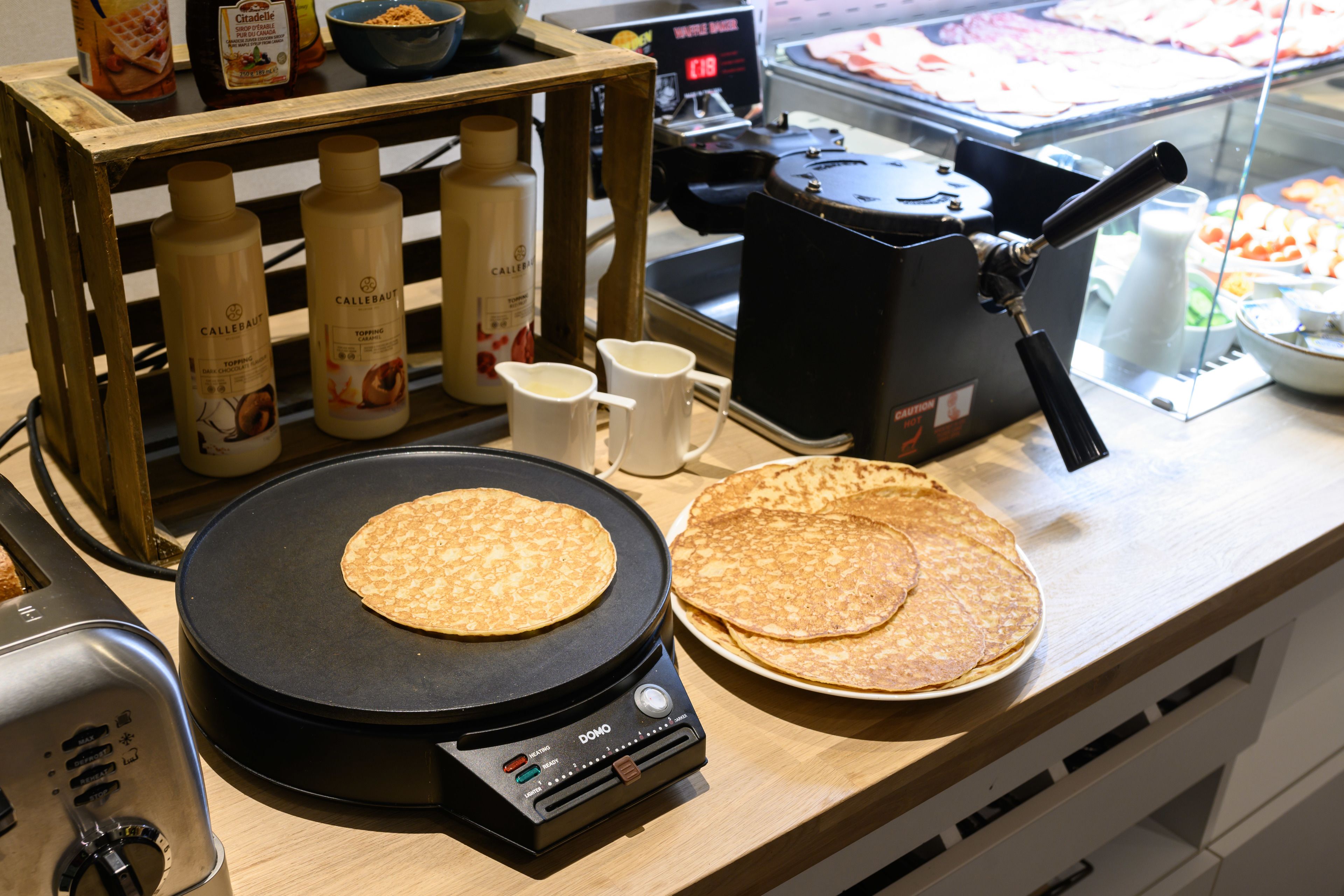 Un piano di lavoro in cucina con una piastra, utensili da cucina e condimenti.