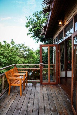 A wooden deck with two wooden chairs and a glass door leading to a room. - AmaresA Resort & Skybar (Ko Pha-ngan)