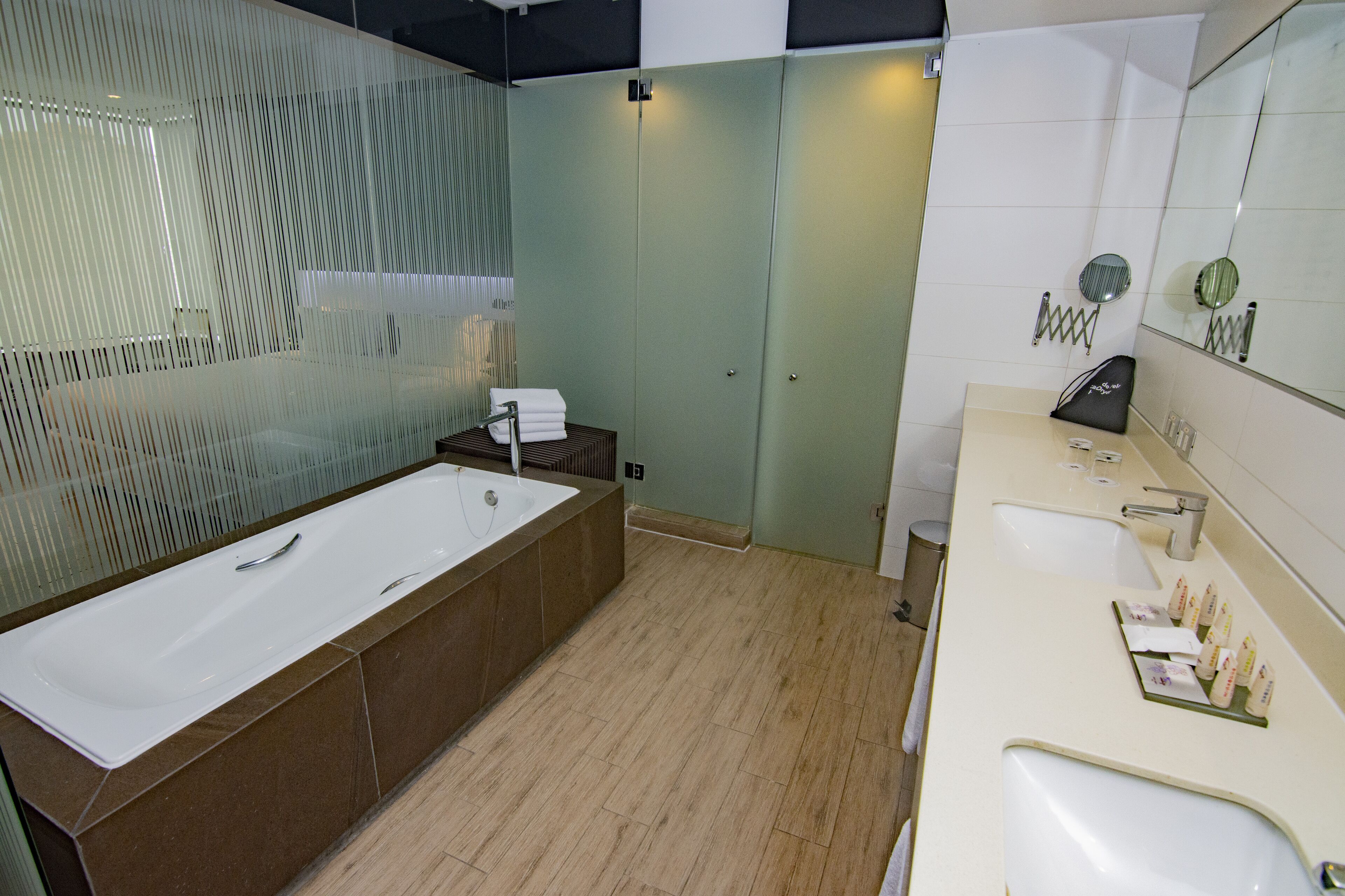 Ein modernes Badezimmer mit einer großzügigen Badewanne, einem separaten Waschbeckenbereich und einem Spiegel über dem Waschbecken.