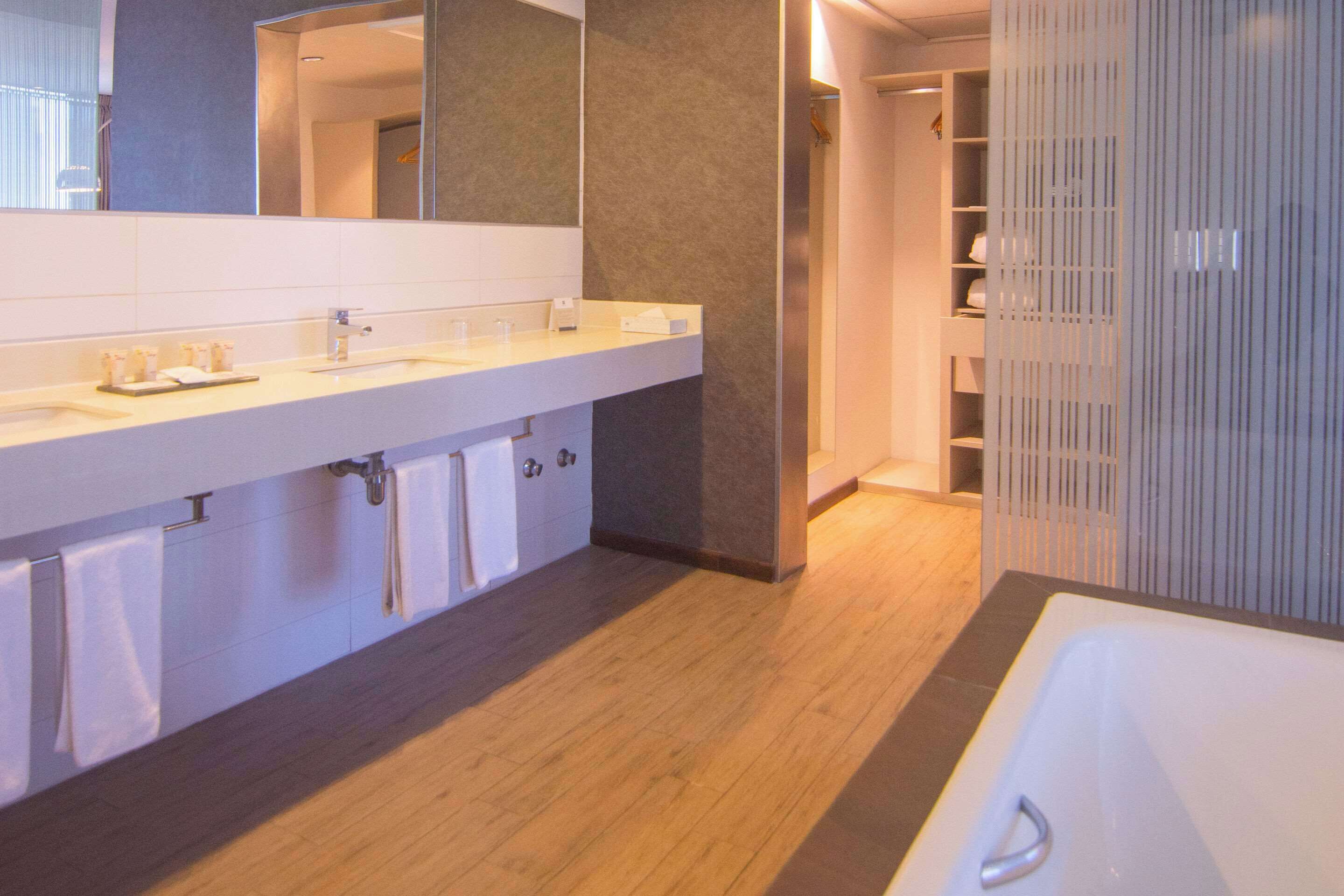 A modern bathroom with a large mirror, a bathtub, and a vanity with a countertop and sink.