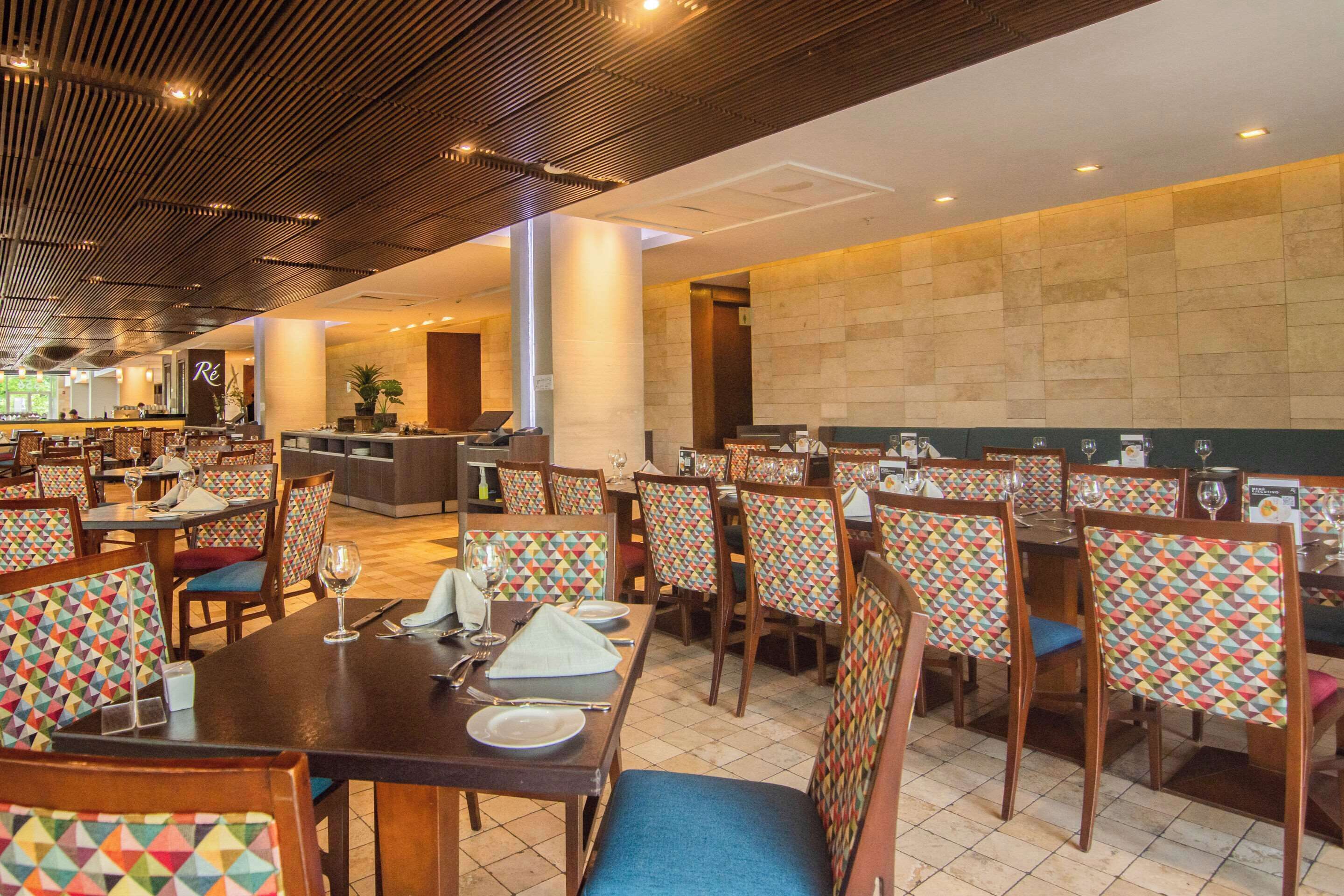 Un restaurante con varias mesas y sillas, algunas con llamativos diseños geométricos.