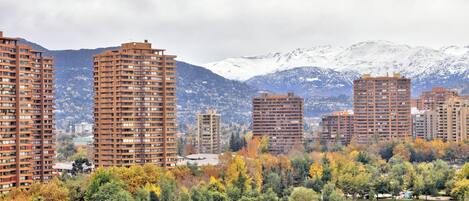 Zona residencial con edificios altos, un parque con árboles y una cadena montañosa al fondo.