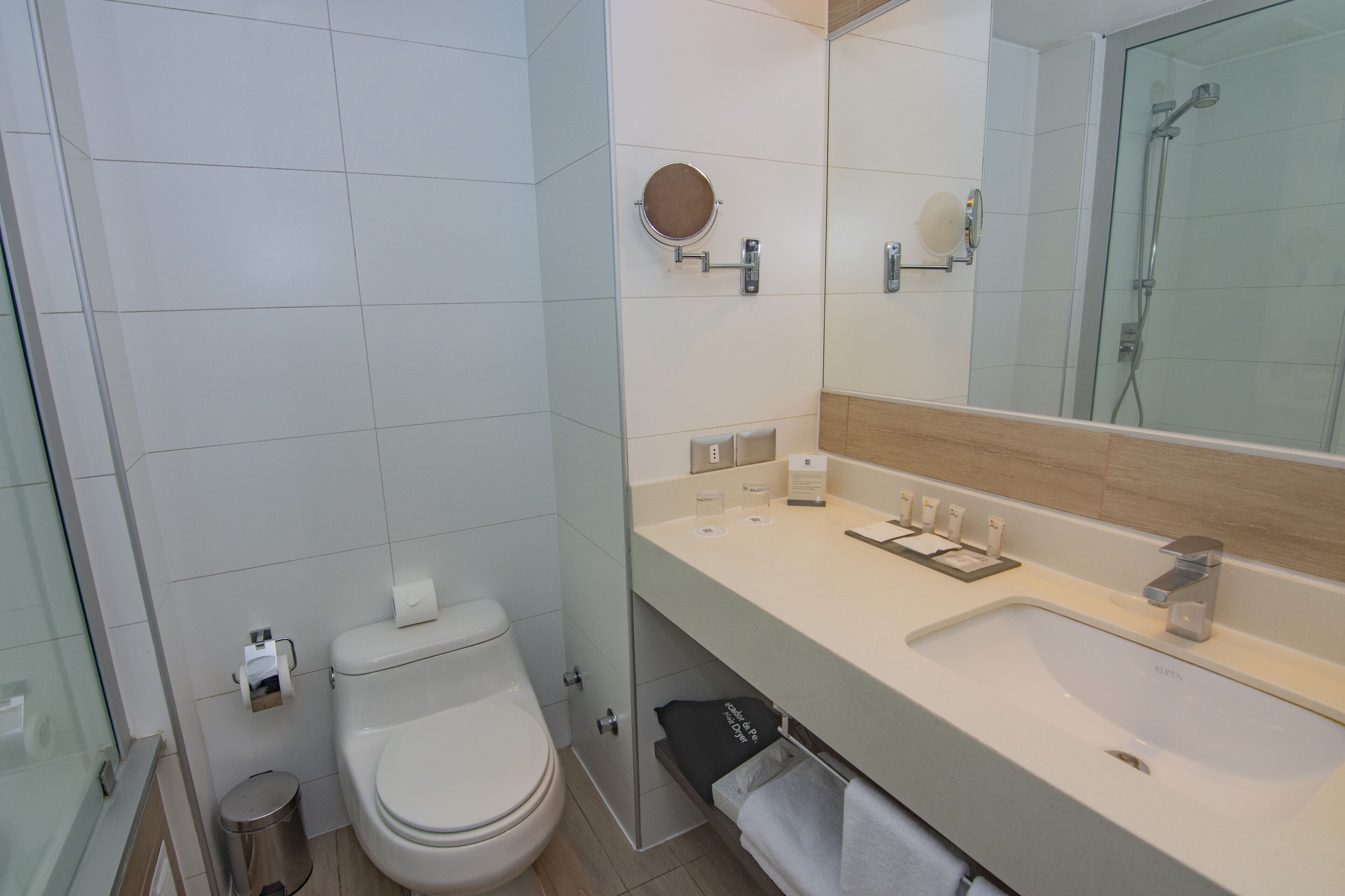 Un baño moderno con inodoro, lavamanos y espejo.