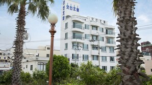 Un edificio de varios pisos con balcones, rodeado de palmeras y otra vegetación.