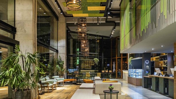 A spacious lobby with seating areas, a reception desk, and a large window overlooking the street. - Ibis Styles Porto Alegre Moinhos de Vento (Porto Alegre)