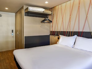 Una habitación de hotel con una cama, un armario y una pared con un diseño geométrico.