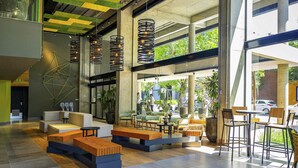 A spacious lobby with modern seating, large windows, and a geometric ceiling design. - Ibis Styles Porto Alegre Moinhos de Vento (Porto Alegre)