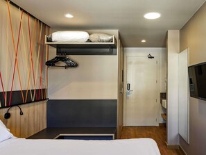 Ein Hotelzimmer mit Bett, Kleiderschrank, Fernseher und Tür.