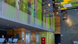 Un hall d’entrée moderne doté d’un comptoir de réception, d’espaces d’attente et d’une installation artistique murale aux motifs géométriques.