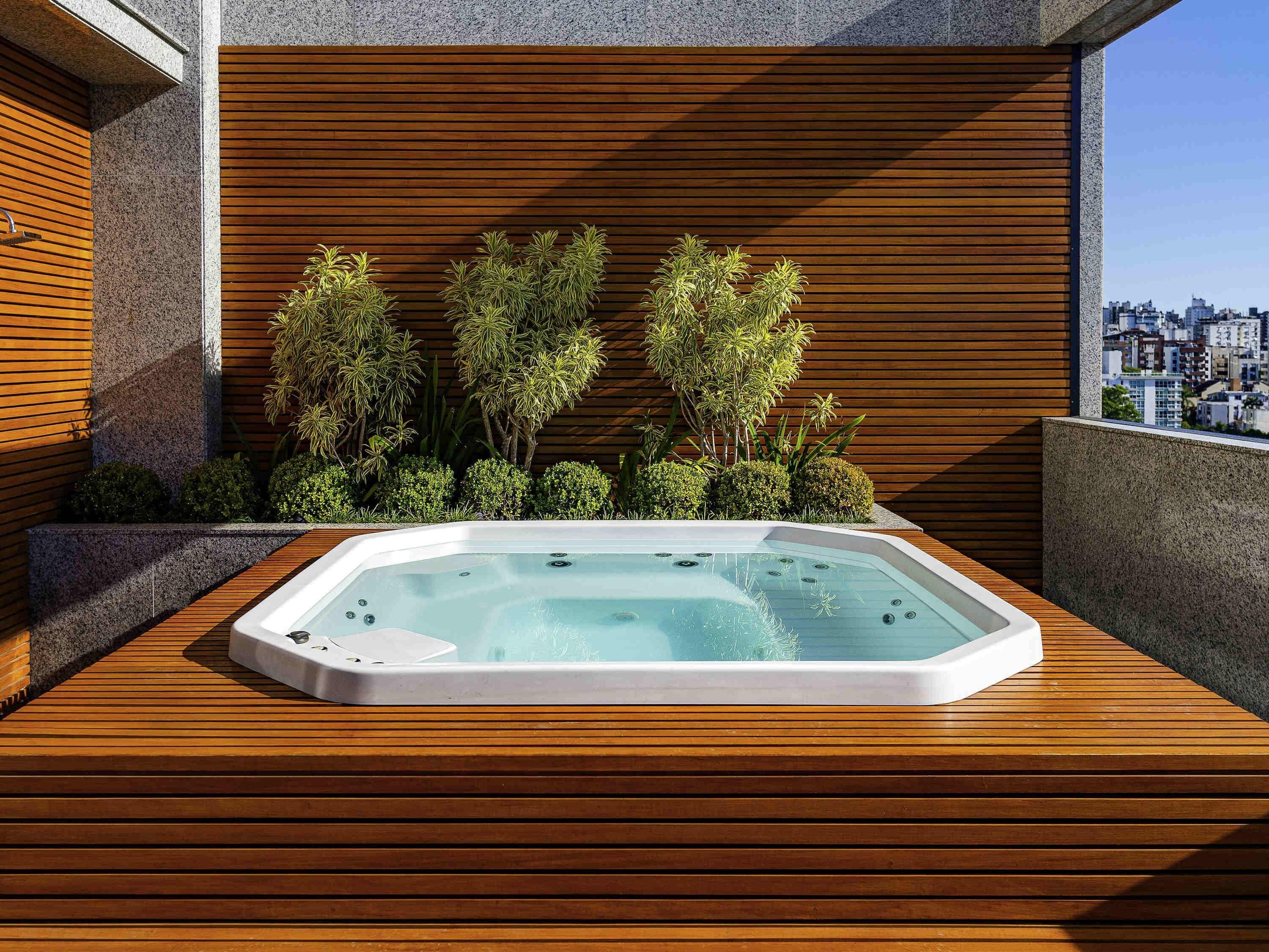 A hot tub on a wooden deck with a city view.