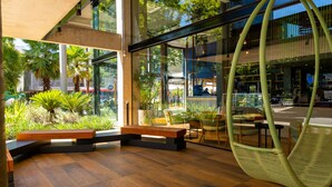 A modern interior with wooden flooring, a hanging chair, and a view of the outdoors through large windows. - Ibis Styles Porto Alegre Moinhos de Vento (Porto Alegre)